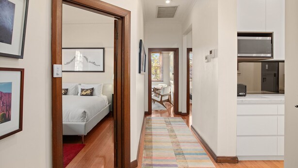 Un couloir d’hôtel avec un lit, un coin cuisine et un espace repas.
