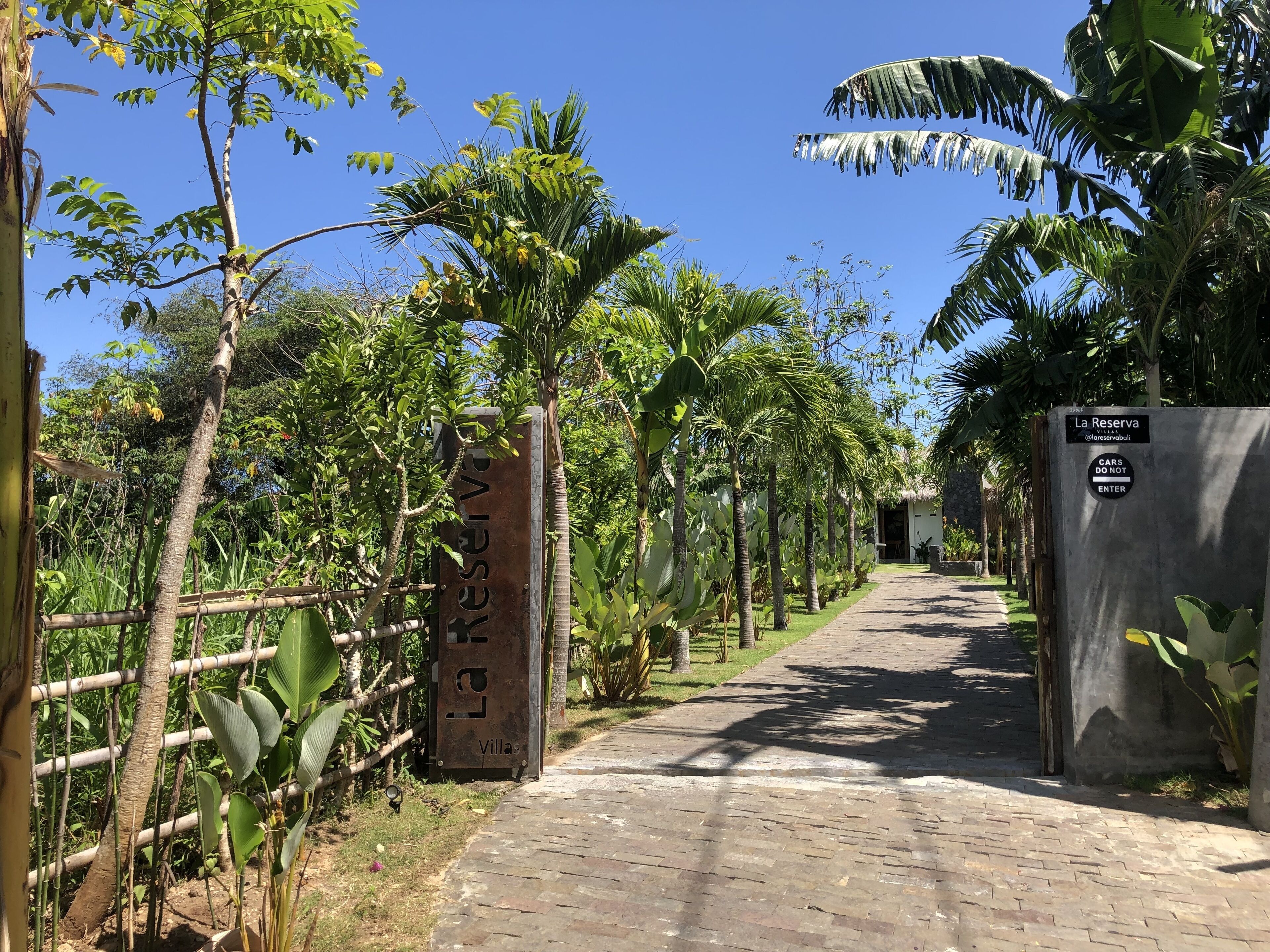 A pathway leading to a gated area with a sign reading "La Reserva Villas @loreservoboii".
