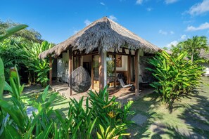 A thatched-roof structure with a glass door, surrounded by lush greenery. - La Reserva Villas Bali (Jimbaran)