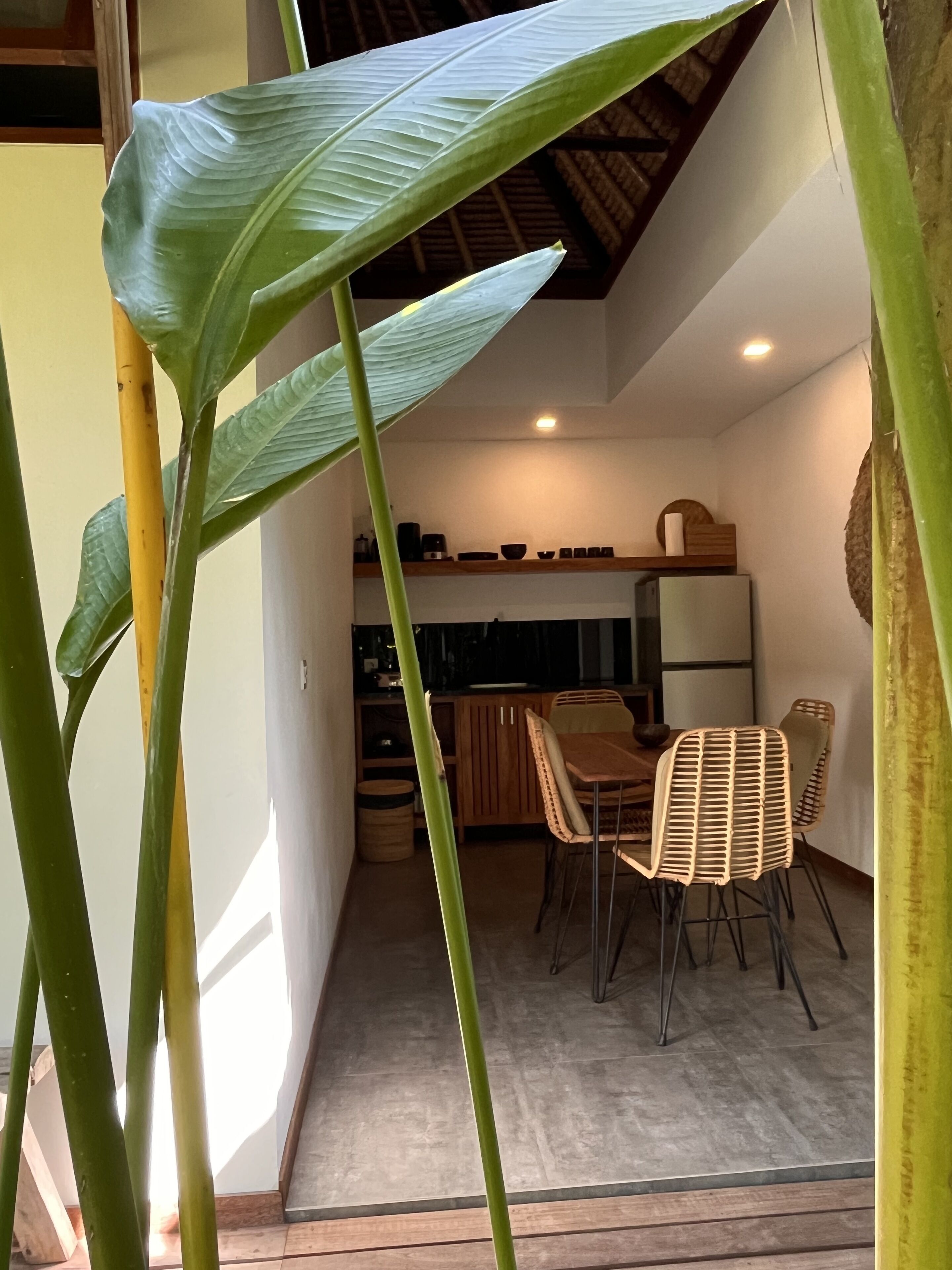 A modern kitchen with wooden cabinets and a dining area with wicker chairs.