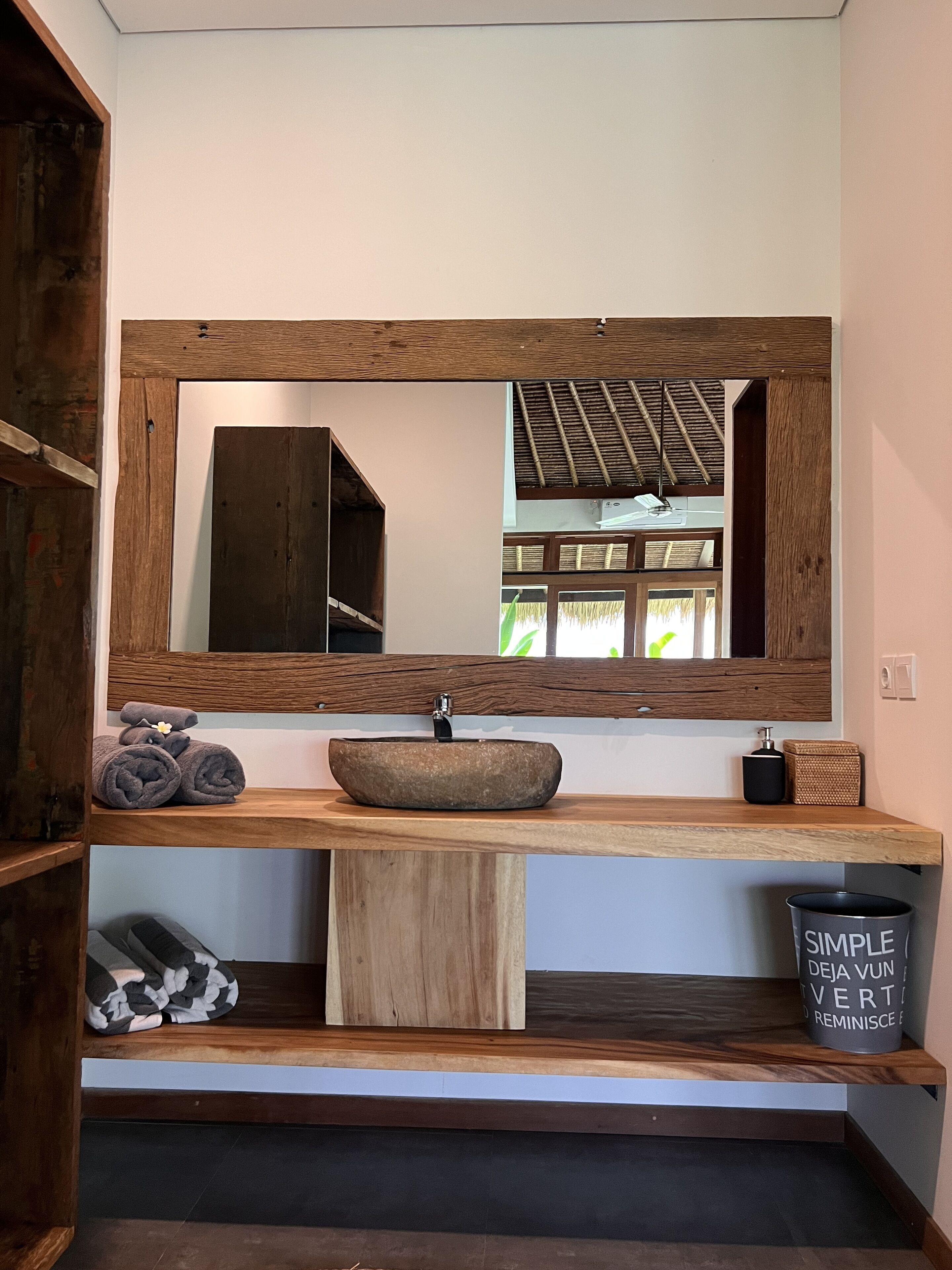 Een badkamer met een houten wastafelmeubel, een grote spiegel en een wastafel.