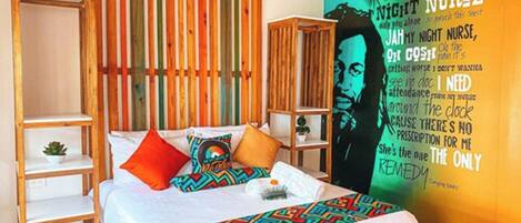 Een slaapkamer met een bed, een houten plank, een wandairconditioner en een kleurrijke muurschildering.