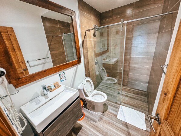 A bathroom with a wooden vanity, a glass shower enclosure, and a mirror above the sink. - In Di House of Reggae Boutique (San Andrés)