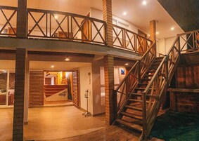 Un amplio vestíbulo de hotel con una escalera de madera y un nivel entre piso.