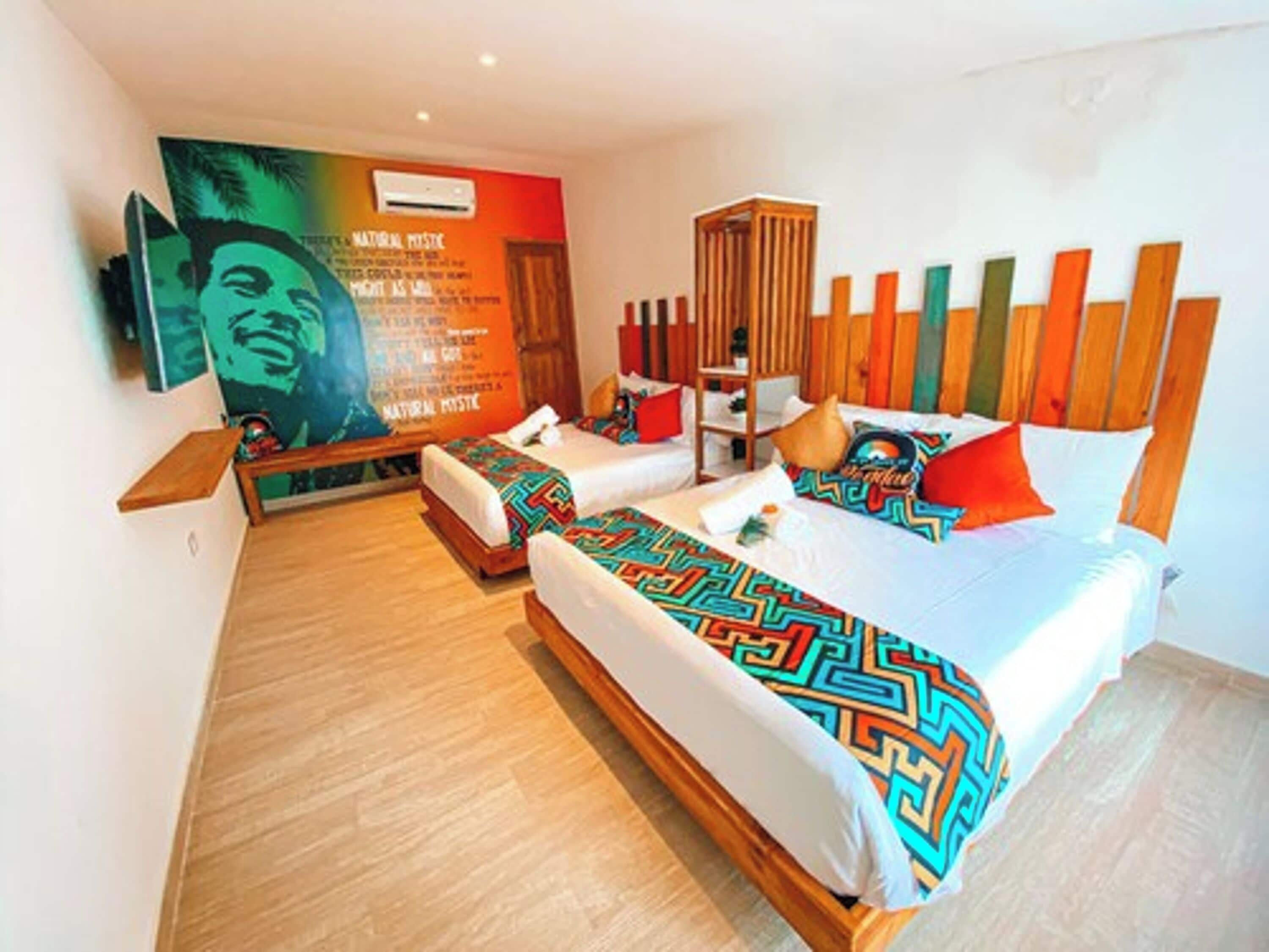 A modern hotel room with a large bed, a wooden headboard, and a vibrant wall mural.
