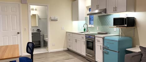 Una cocina compacta con microondas, horno y un refrigerador azul antiguo.