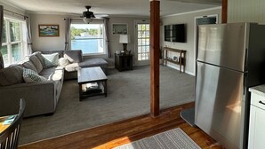 A spacious living area with a sofa, coffee table, and a large window offering a view of the outdoors.