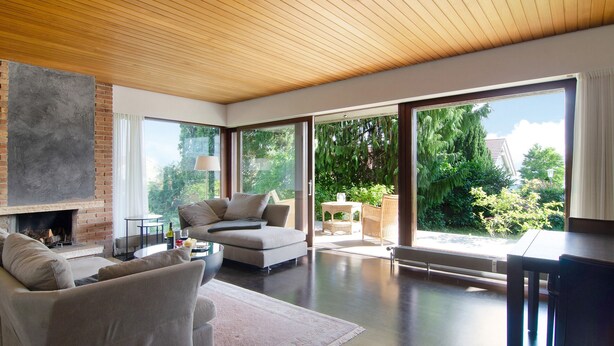 A modern living room with a fireplace, a sofa, a dining table, and large sliding glass doors to a garden. - DOMICILE RELAX" between Salem Monastery & Heiligenberg Castle - comfort on 80sqm (Salem)