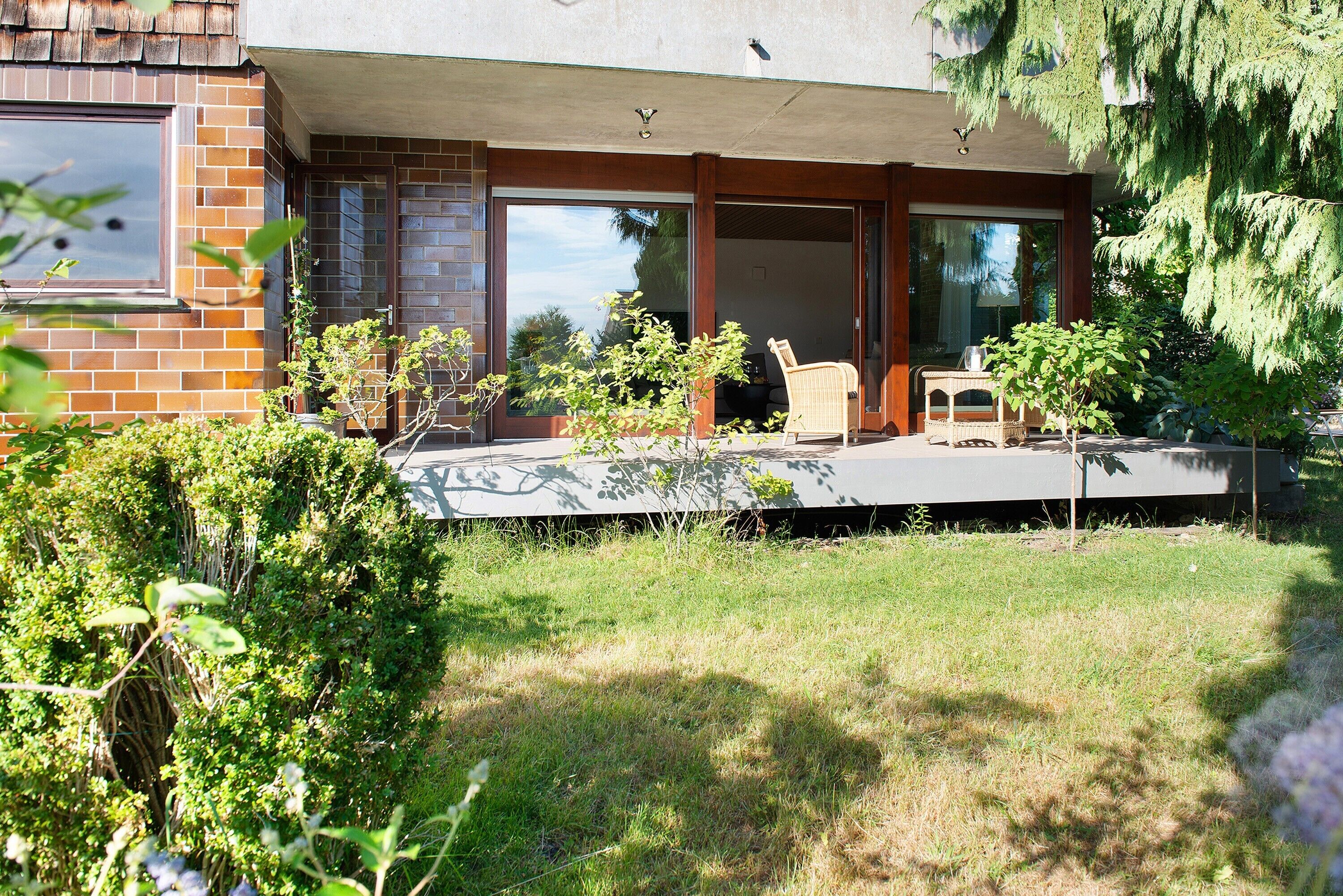 A modern house with a patio, a chair, and a small table.