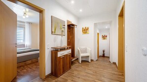 Een modern interieur met een houten vloer, een witte stoel, een houten kast en een bed op de achtergrond.