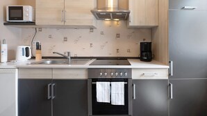 Een moderne keuken met een magnetron, fornuis, oven en koffiezetapparaat.