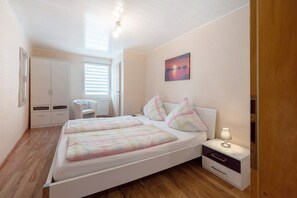 Une chambre avec deux lits, une table de chevet, un bureau et une fenêtre avec des stores.