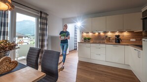 A modern kitchen with white cabinets, a wooden countertop, and a view of mountains through large windows. - Apartment 'Eve' with Mountain View, Balcony and Wi-Fi (Söll)