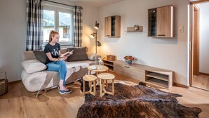 A modern living room with a sofa, a coffee table, a lamp, and a large rug. - Apartment 'Eve' with Mountain View, Balcony and Wi-Fi (Söll)