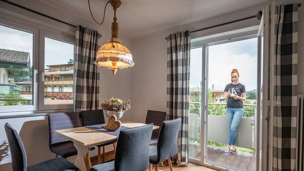 A dining area with a table and chairs, a hanging light fixture, and a view through a sliding glass door. - Apartment 'Eve' with Mountain View, Balcony and Wi-Fi (Söll)