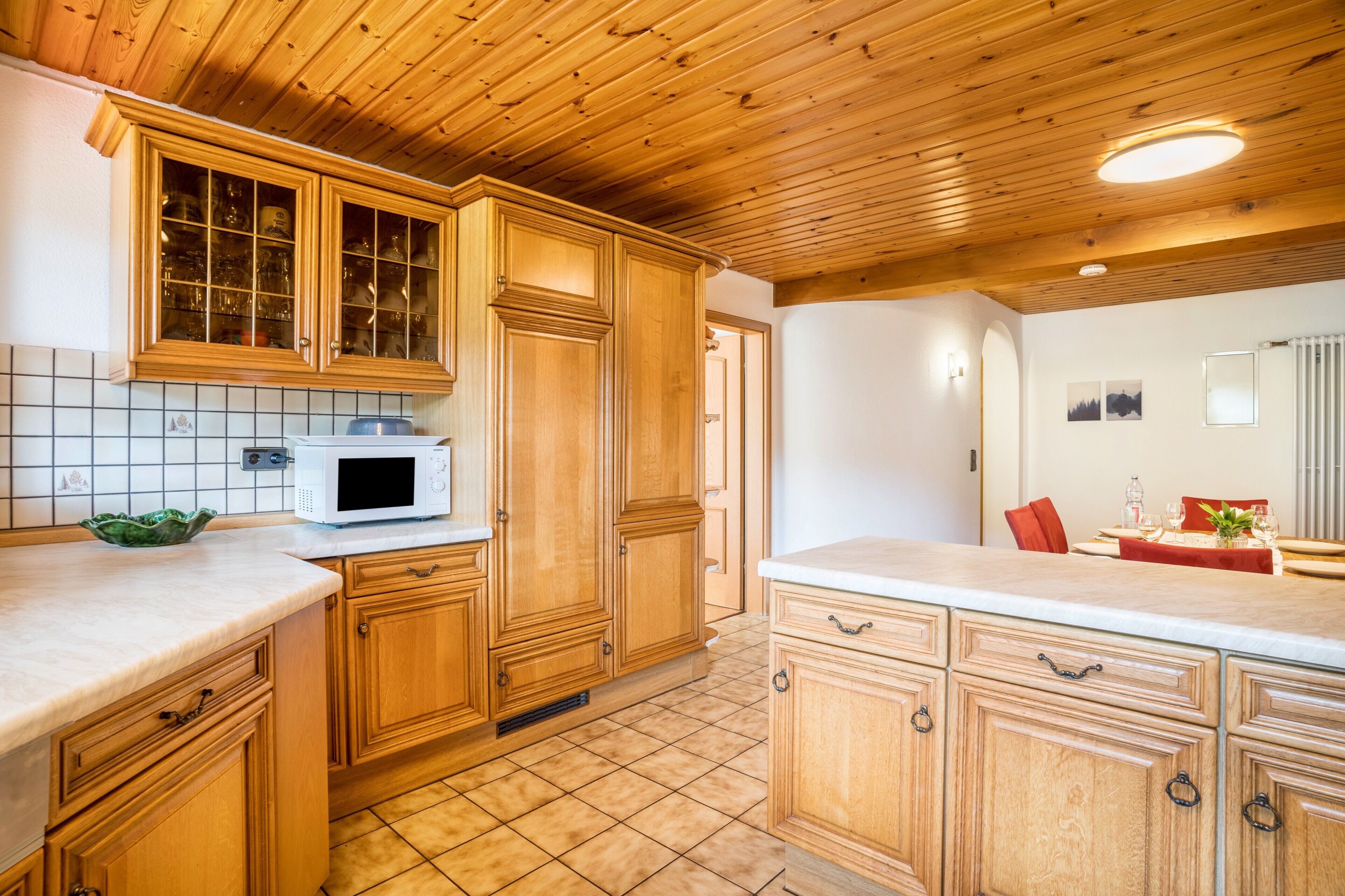 A kitchen with wooden cabinets, a microwave, and a tiled backsplash.