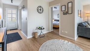 A modern living room with a sofa, a round rug, a wall clock, and a small table with a plant. - Apartment "Haus Dünenbutze" with Shared Garden & Wi-Fi (Büsum)