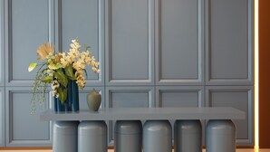 Quarto moderno com parede cinza, mesa branca e um vaso de flores.