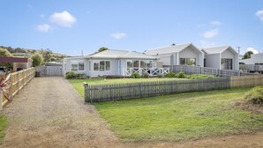 A row of white mobile homes with a gravel driveway and a wooden fence.