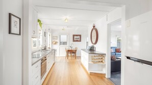 A modern kitchen with a central island, wooden flooring, and white cabinetry.