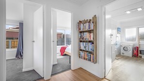A room with a wooden bookshelf, a washing machine, and a laundry area.
