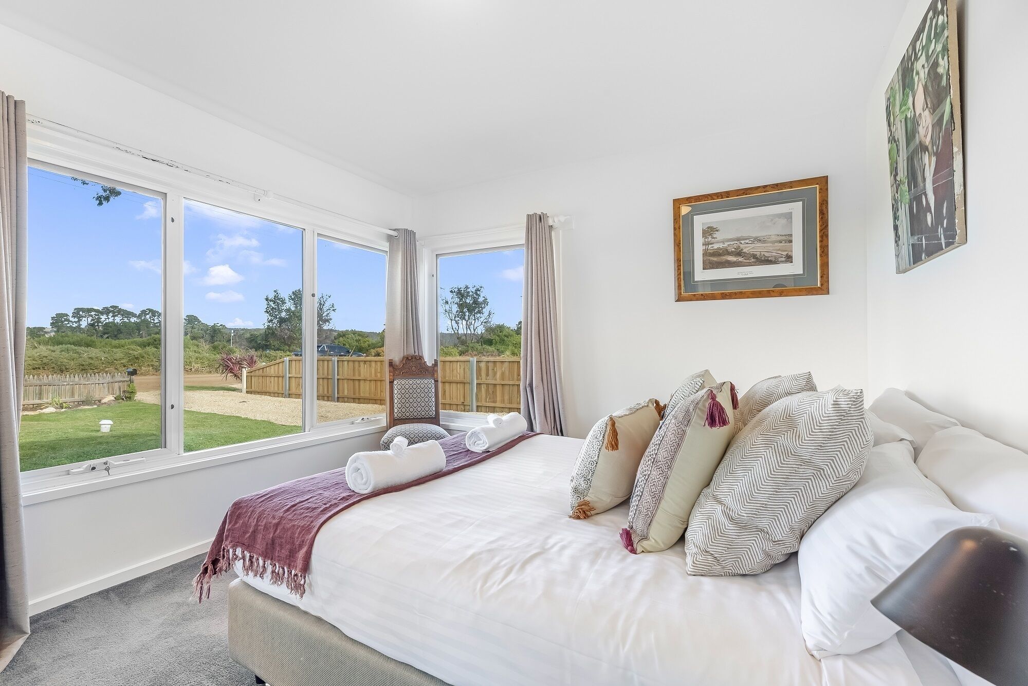 Un dormitorio con una cama grande, vistas al exterior y un cuadro en la pared.