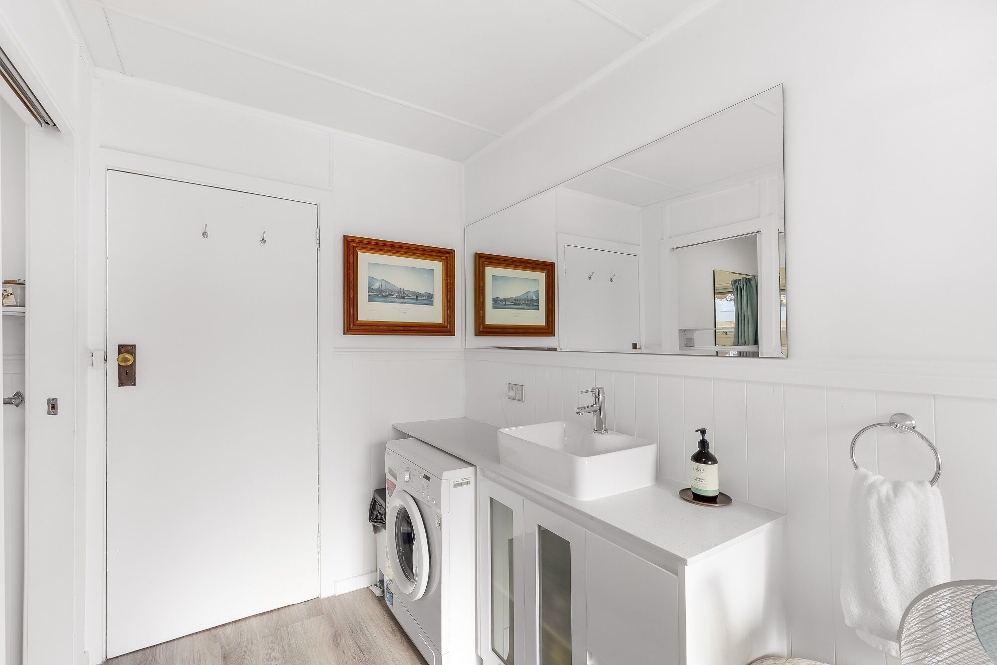 Un baño moderno con lavadora incorporada, un lavamanos y un espejo grande.