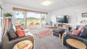 A modern living room with a large TV, leather sofas, and a view of the outdoors.
