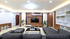 A modern living room with a flat-screen TV, a sofa set, a coffee table, and a bookshelf. - Paradise Home Xuan La (Hanoi)