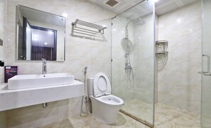 Une salle de bain moderne avec une douche à parois de verre, un lavabo blanc et des toilettes.