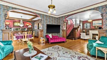 Ein geräumiges Wohnzimmer mit Kamin, einem Essbereich und einer Treppe, die zu einer oberen Ebene führt.