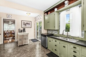 A kitchen with green cabinets, a sink, and a dining area with a table and chairs.