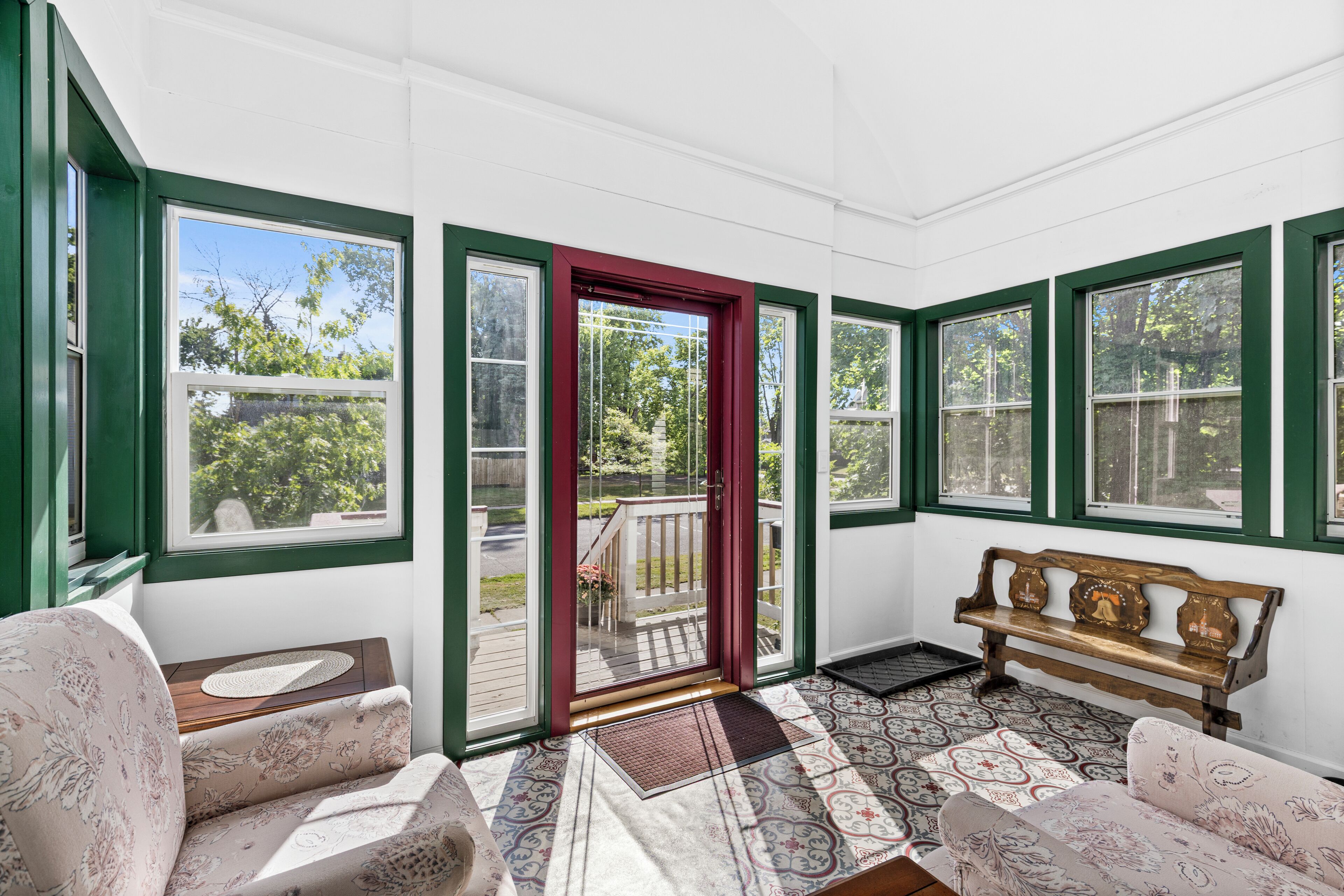 A sunroom with a bench, a door, and patterned flooring.