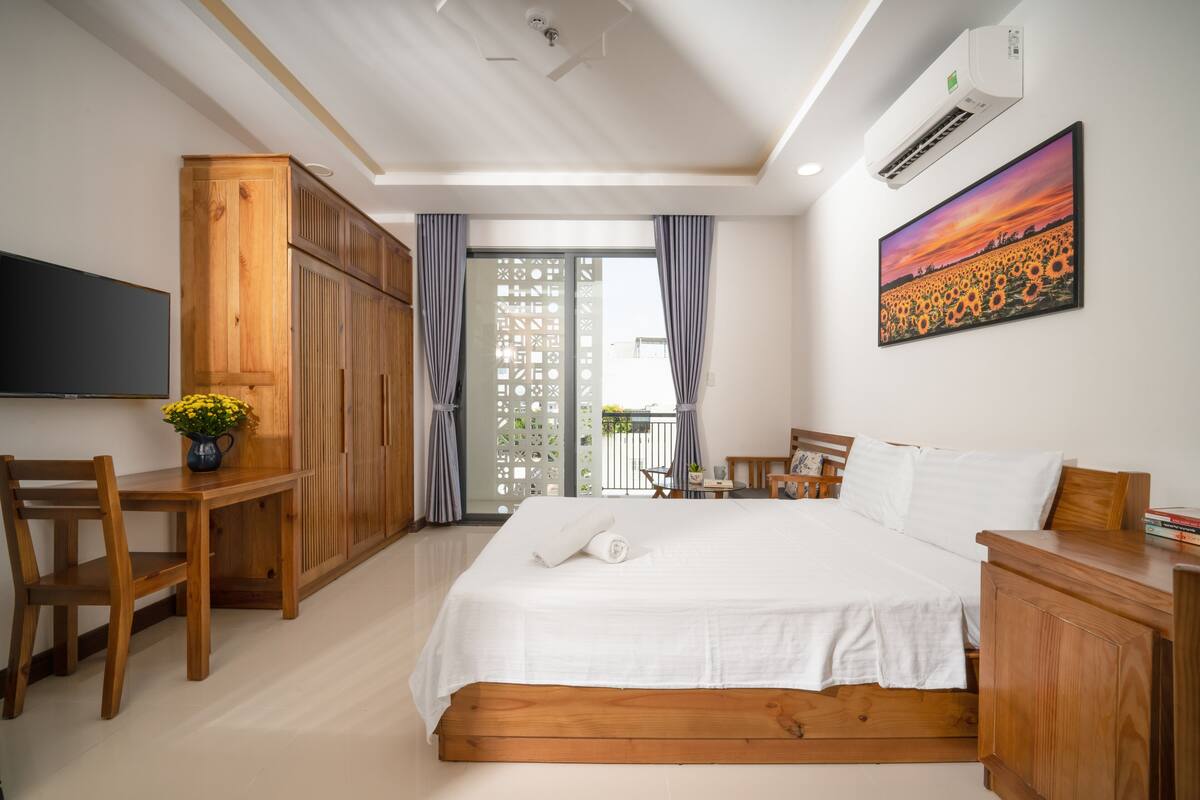 Un dormitorio con cama, muebles de madera, televisor y un cuadro.