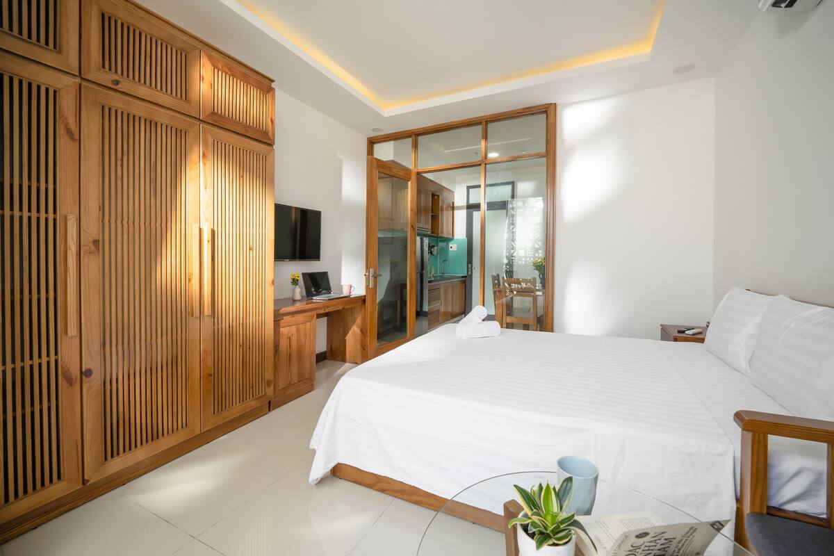 Un dormitorio espacioso con una cama grande, un armario de madera y un escritorio con computadora.