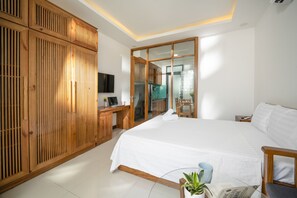 Un dormitorio espacioso con una cama grande, un armario de madera y un escritorio con computadora.