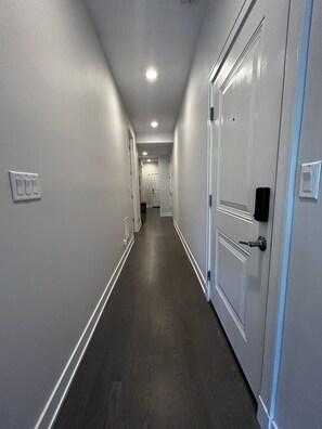 Stylish hallway with doors leading to a room beyond, featuring modern handles and mounted devices.