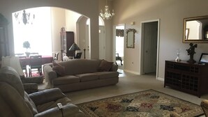 Una sala de estar con un sofá, sillones, una alfombra y un candelabro.