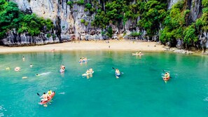 Une mer turquoise aux eaux limpides, où l’on peut voir des kayaks et des nageurs.