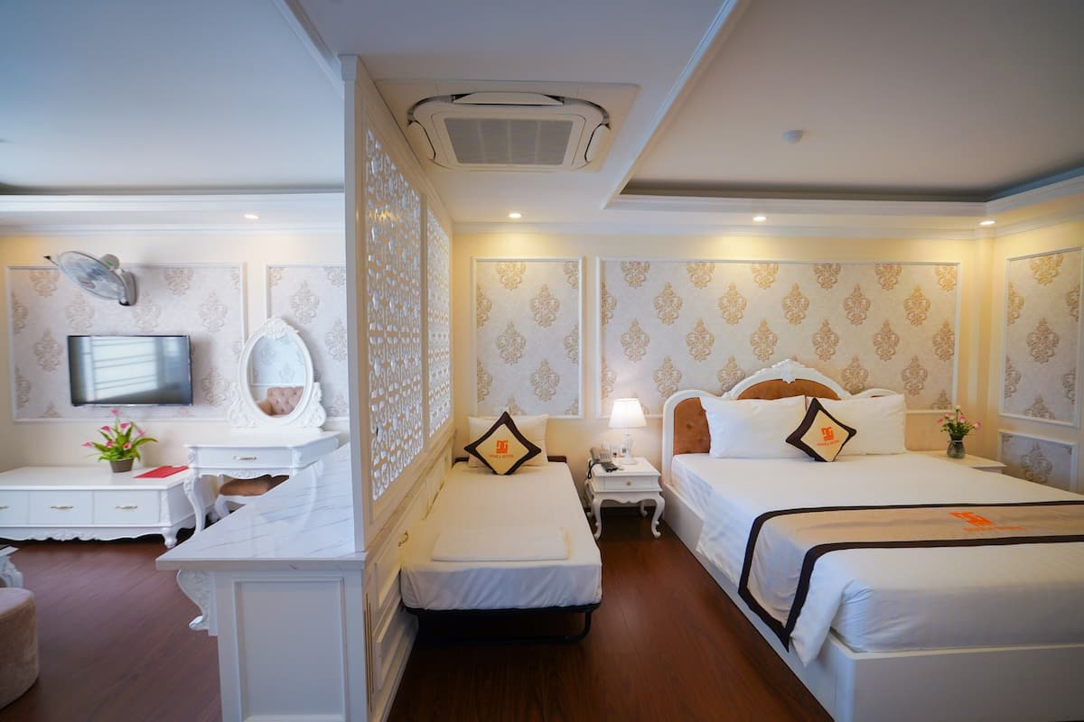 A hotel room with two beds, a desk, a TV, and a decorative wall.