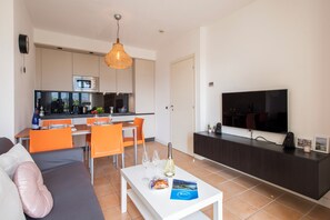 Uma sala de estar moderna com sofá, área de jantar, cozinha e televisão.