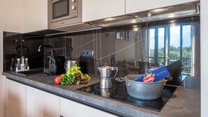 A modern kitchen with a black countertop, stainless steel appliances, and a view of the outdoors through a window.