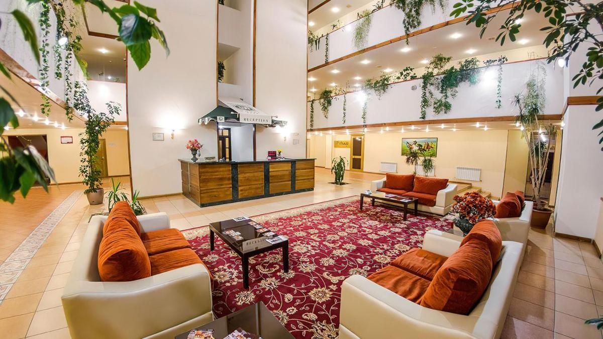 A spacious lobby with a reception desk, seating area, and multiple levels with plants.