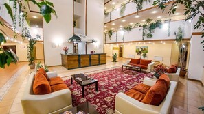 A spacious lobby with a reception desk, seating area, and multiple levels with plants.