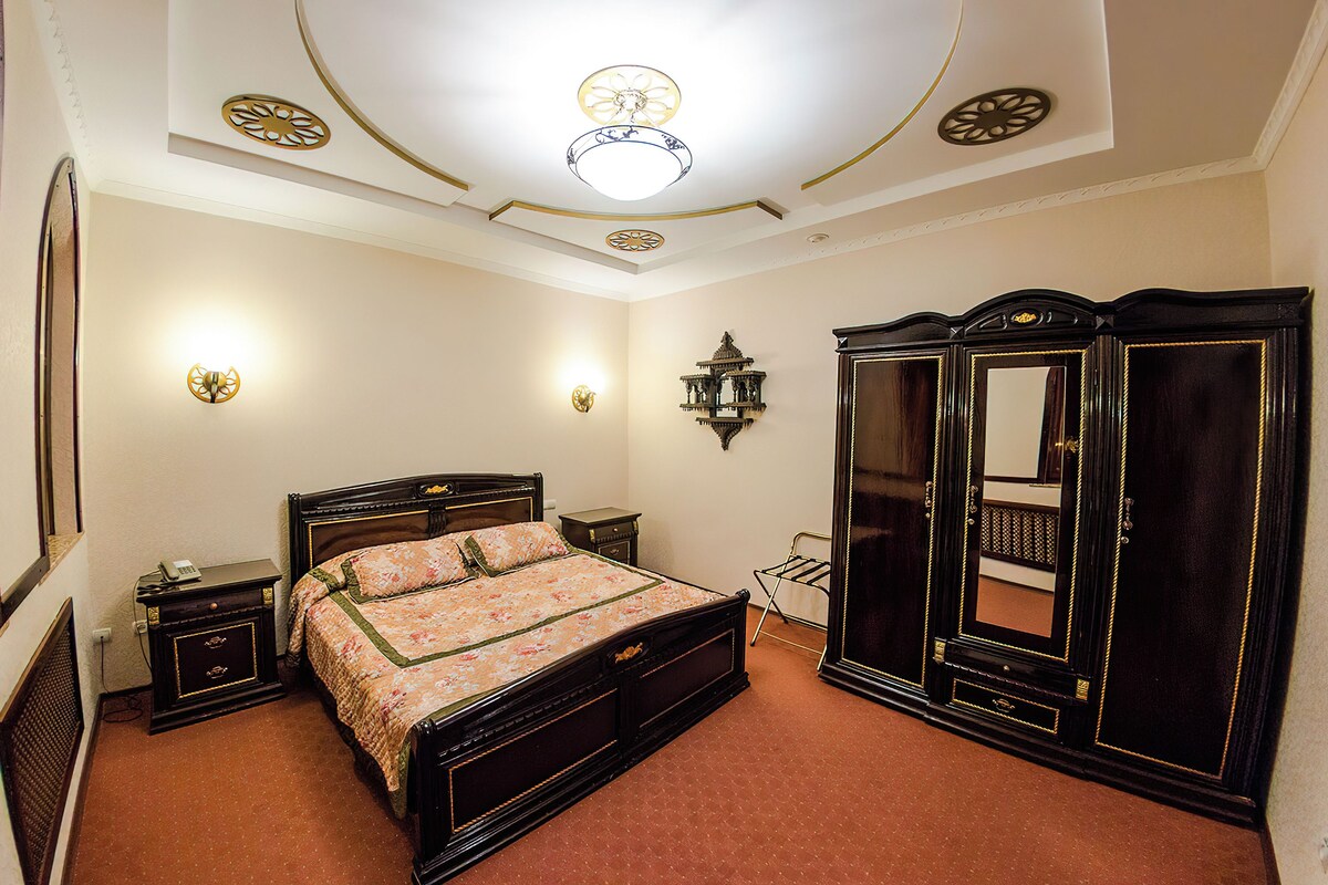 A bedroom with a bed, bedside tables, a wardrobe, and decorative wall sconces.