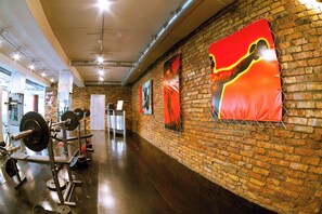 Une salle de sport avec des murs en briques, du matériel d’exercice et des affiches.