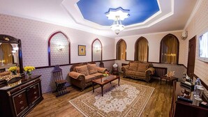 A traditional interior with sofas, a coffee table, a patterned rug, and a chandelier. - Reikartz Karaganda (Karagandy)