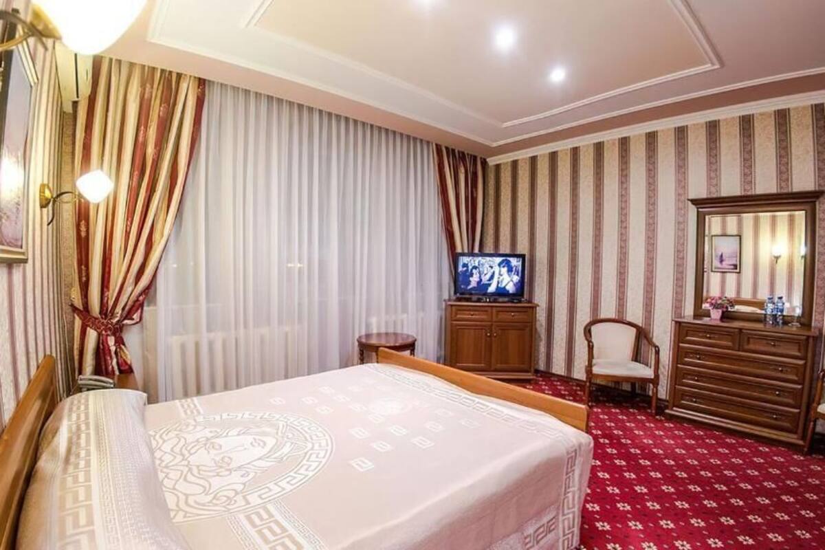 Quarto de hotel com uma cama, televisão, penteadeira e espelho.
