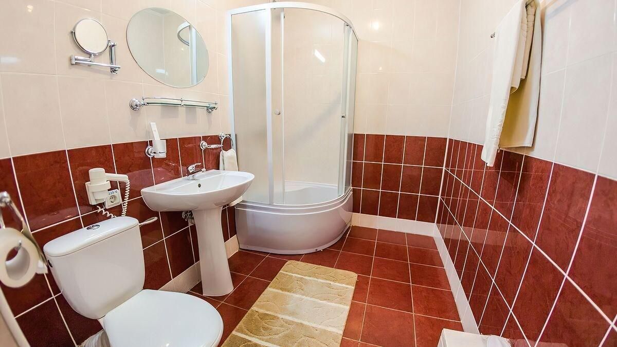 A bathroom with a toilet, sink, shower, and a towel rack.