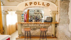 A bar area with a stone fireplace, two stools, and a sign reading 'APOLLO'. - Reikartz Karaganda (Karagandy)